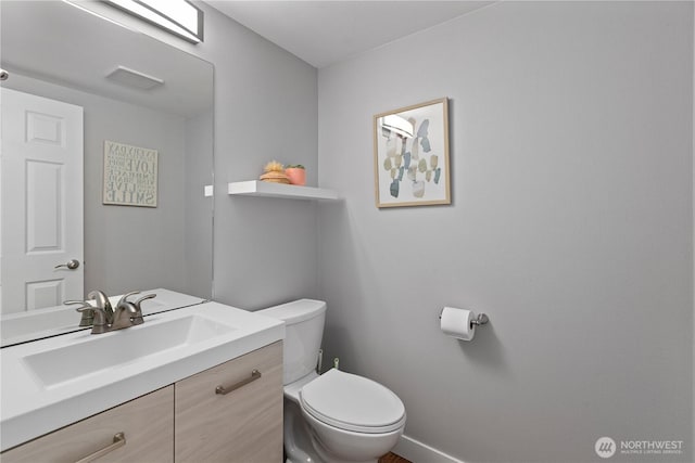 half bathroom with toilet, vanity, and baseboards