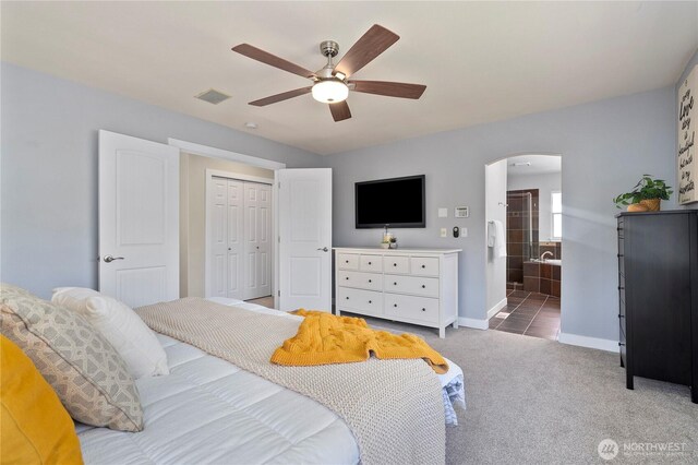 bedroom featuring arched walkways, light carpet, a closet, baseboards, and a ceiling fan