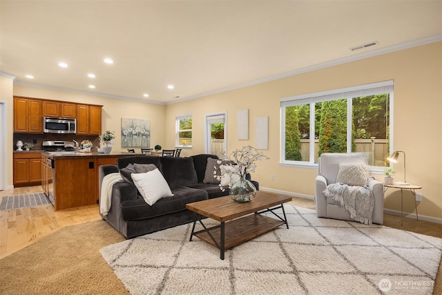 living room featuring crown molding, healthy amount of natural light, baseboards, recessed lighting, and light wood finished floors