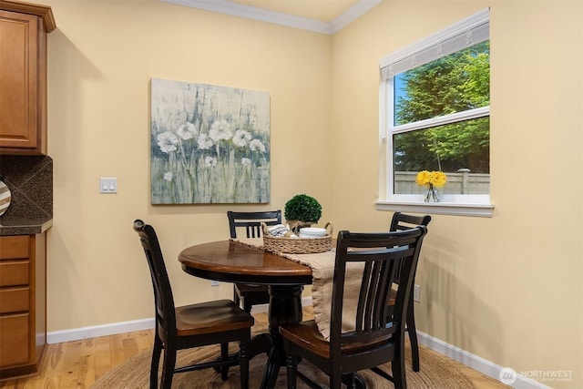 dining area featuring ornamental molding, light wood-type flooring, and baseboards