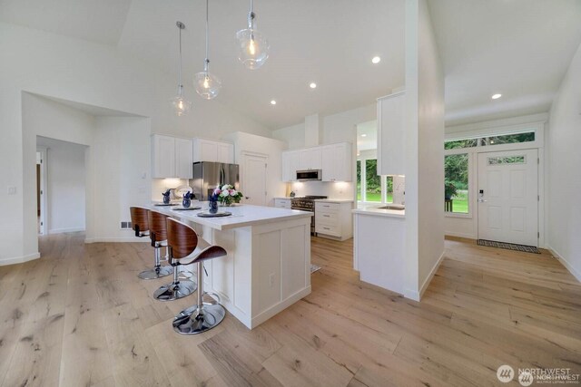 39195 Blackmouth Pl NE, Hansville, WA 98340 - kitchen with stainless steel appliances, white cabinetry, light wood-type flooring, light countertops, and a kitchen island