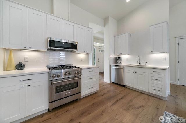 39195 Blackmouth Pl NE, Hansville, WA 98340 - kitchen featuring appliances with stainless steel finishes, a sink, tasteful backsplash, white cabinetry, and light wood-style flooring