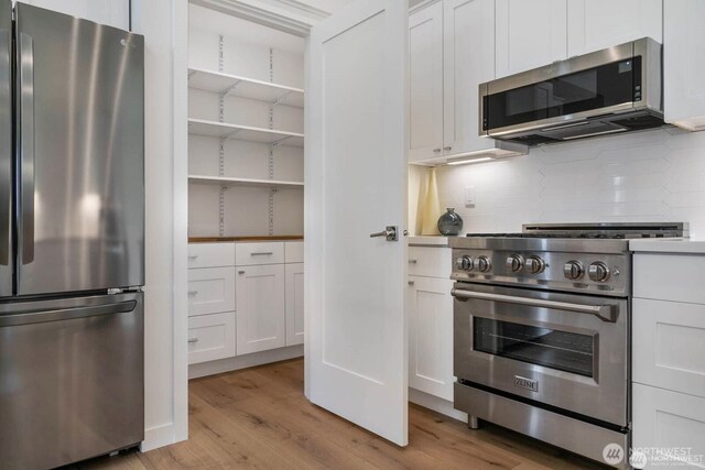 39195 Blackmouth Pl NE, Hansville, WA 98340 - kitchen featuring stainless steel appliances, light wood-type flooring, decorative backsplash, and white cabinets