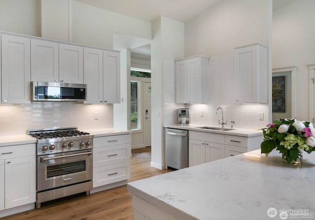 39195 Blackmouth Pl NE, Hansville, WA 98340 - kitchen featuring stainless steel appliances, a sink, light wood-type flooring, backsplash, and a high ceiling