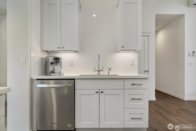 39195 Blackmouth Pl NE, Hansville, WA 98340 - kitchen with stainless steel dishwasher, a sink, white cabinetry, wood finished floors, and baseboards