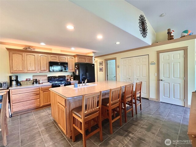 kitchen featuring black appliances, light countertops, a kitchen bar, recessed lighting, and an island with sink
