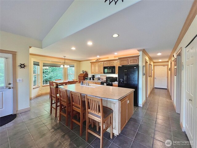 kitchen featuring black appliances, a sink, recessed lighting, a kitchen bar, and a spacious island