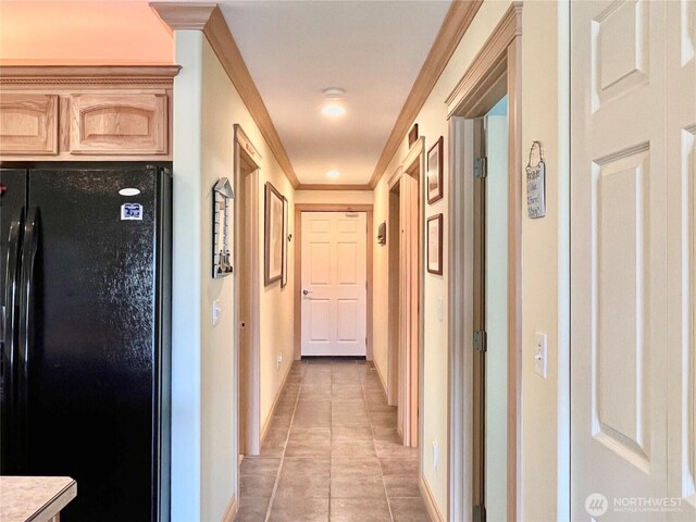 hall with light tile patterned flooring, baseboards, and crown molding