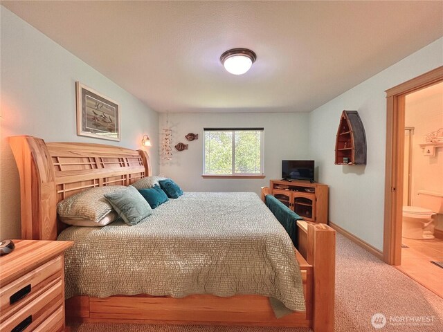 carpeted bedroom featuring baseboards and connected bathroom