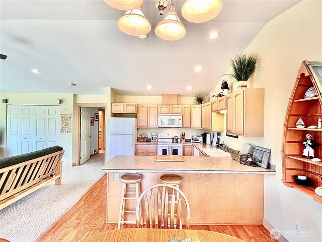kitchen featuring white appliances, a peninsula, light brown cabinets, light countertops, and recessed lighting