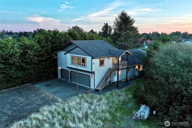 view of front of house with driveway, an attached garage, and stairs