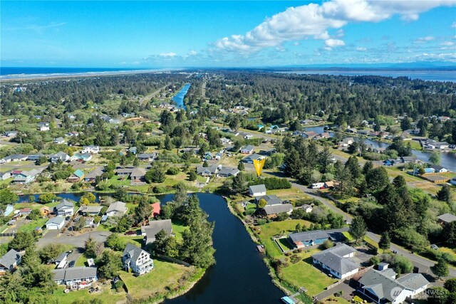 aerial overview of property's location featuring a nearby body of water, a forest, and nearby suburban area