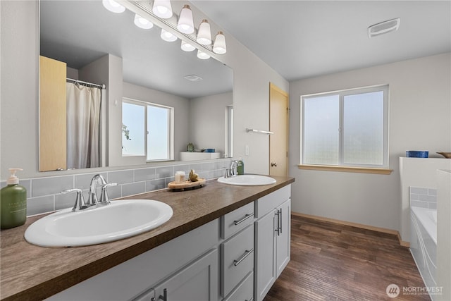 3612 64th St E, Tacoma, WA 98443 - full bathroom with double vanity, tasteful backsplash, a garden tub, and wood finished floors