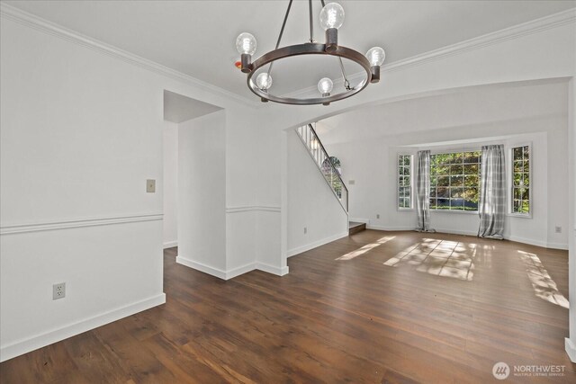 unfurnished living room with a chandelier, stairway, crown molding, wood finished floors, and baseboards