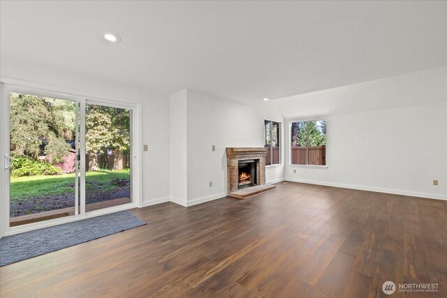 unfurnished living room featuring plenty of natural light, dark wood-style flooring, baseboards, and recessed lighting