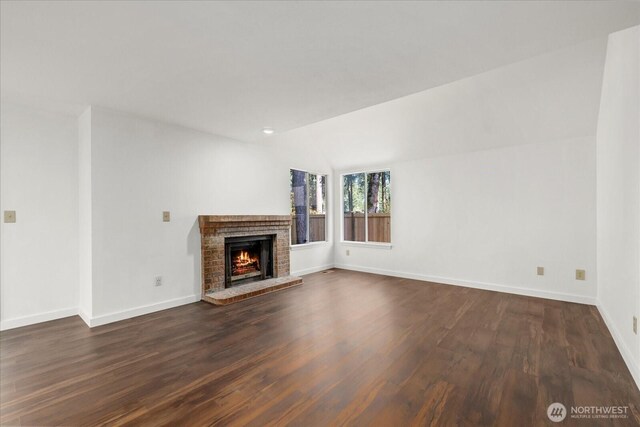 unfurnished living room featuring dark wood-style floors, baseboards, and a fireplace