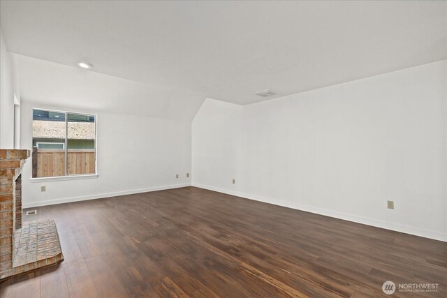 unfurnished living room with dark wood finished floors, baseboards, and a fireplace