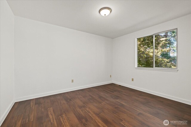 empty room with dark wood-type flooring and baseboards