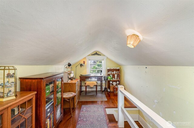home office with wood finished floors, lofted ceiling, and a textured ceiling