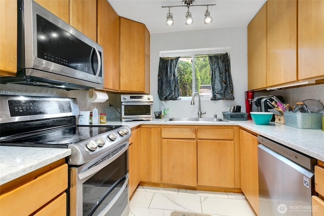 kitchen featuring appliances with stainless steel finishes, a sink, light countertops, decorative backsplash, and light marble finish floors