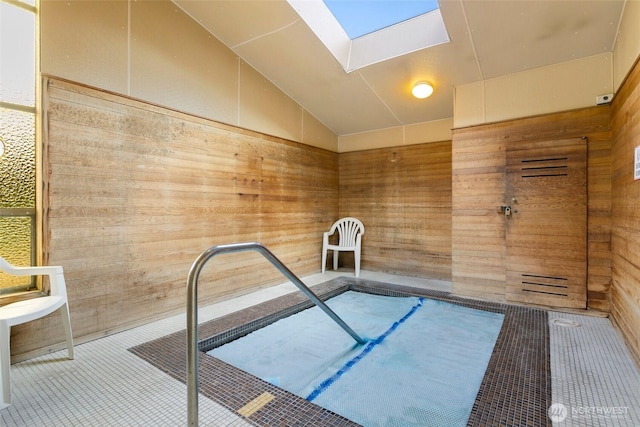 misc room featuring wooden walls, a skylight, and vaulted ceiling
