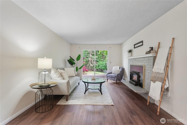 living room featuring a textured ceiling, dark wood-style flooring, baseboards, and a brick fireplace