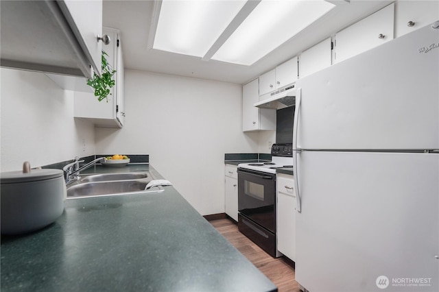 kitchen featuring freestanding refrigerator, black range with electric stovetop, a sink, under cabinet range hood, and white cabinets