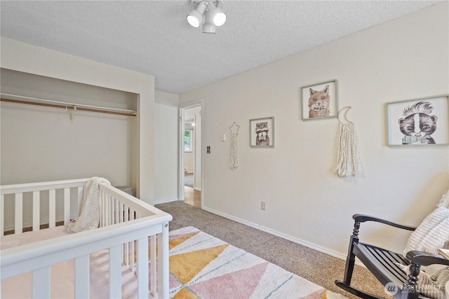 bedroom with carpet flooring, a closet, a textured ceiling, and baseboards