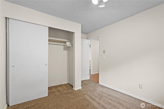 unfurnished bedroom featuring carpet, a closet, a textured ceiling, and baseboards