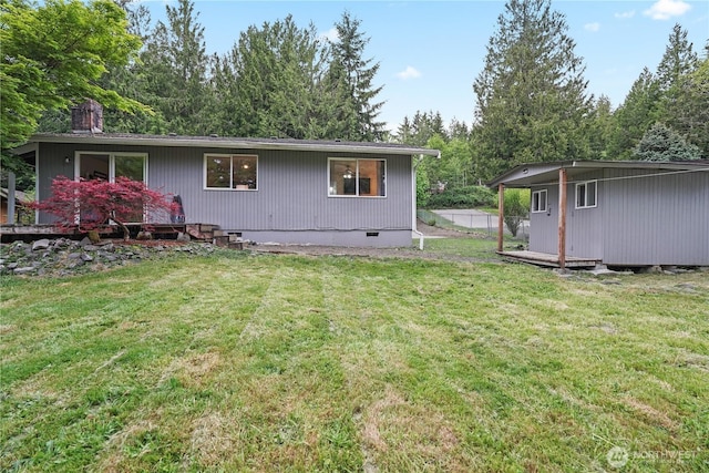 back of property with crawl space, a chimney, and a lawn
