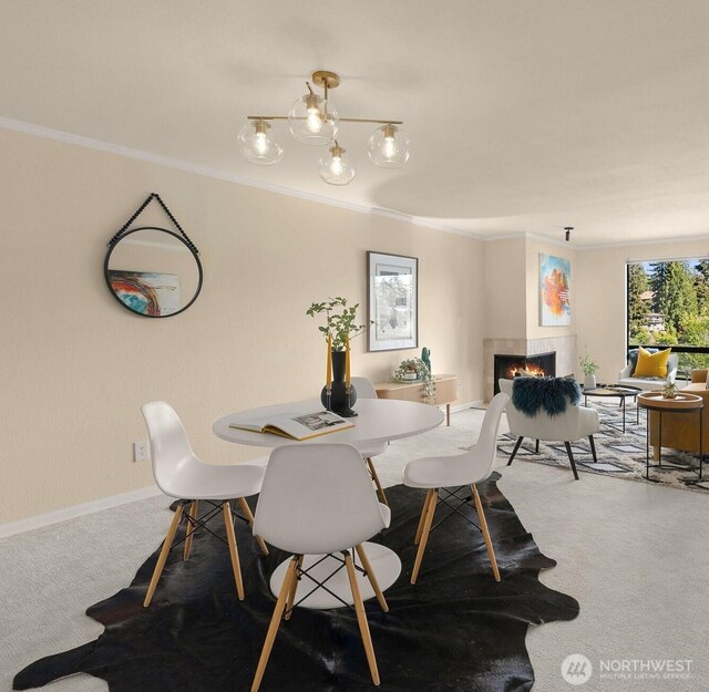 carpeted dining area with a tiled fireplace, ornamental molding, and baseboards