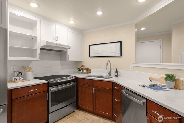 kitchen with appliances with stainless steel finishes, a sink, under cabinet range hood, ornamental molding, and white cabinetry