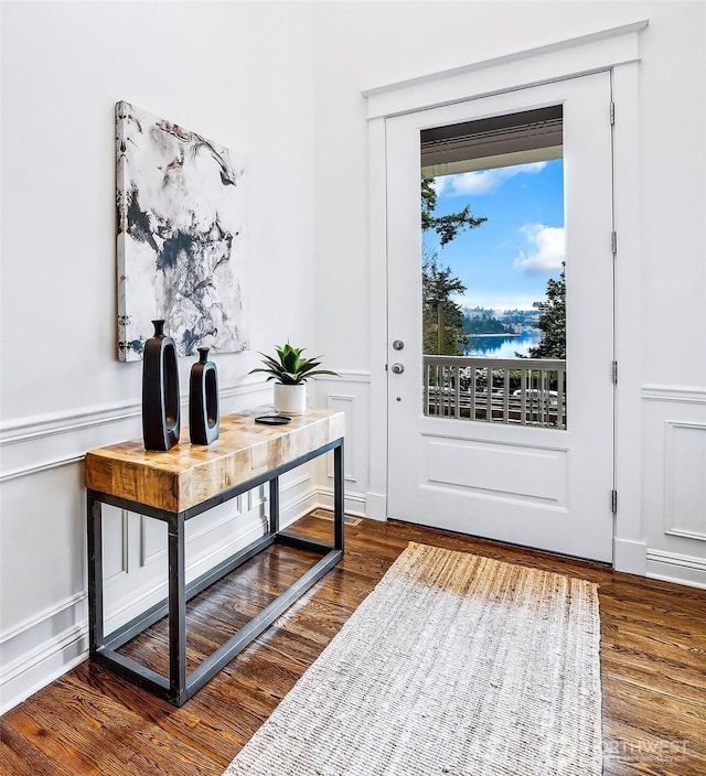 entryway featuring wood finished floors, a decorative wall, and wainscoting