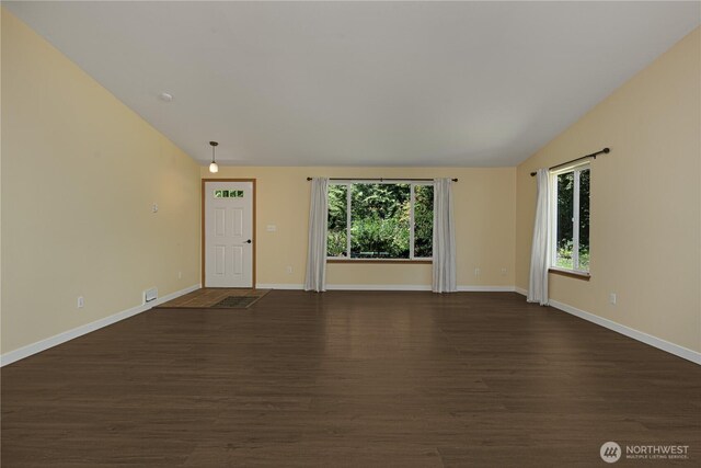 unfurnished living room featuring dark wood-style flooring, baseboards, and vaulted ceiling