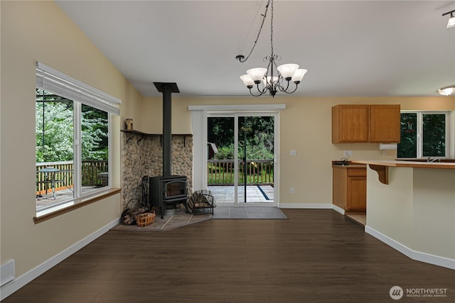 kitchen featuring a wood stove, plenty of natural light, dark wood-type flooring, and baseboards