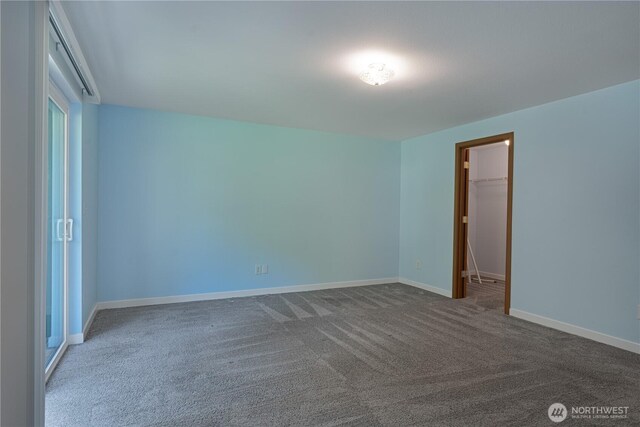 carpeted empty room featuring baseboards