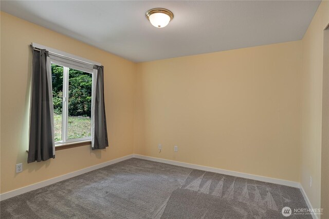 spare room with dark carpet and baseboards
