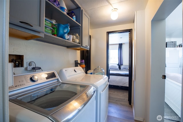 laundry area with washer and dryer, cabinet space, and wood finished floors