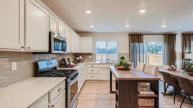 kitchen featuring recessed lighting, white cabinetry, light countertops, backsplash, and appliances with stainless steel finishes