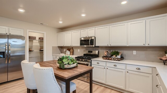 kitchen featuring white cabinets, light countertops, appliances with stainless steel finishes, and light wood-style flooring