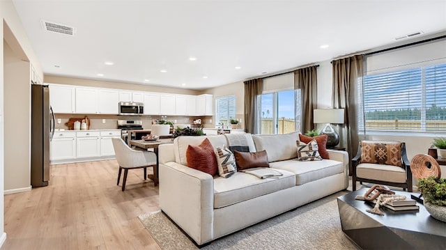 living room featuring visible vents, light wood-style flooring, and recessed lighting