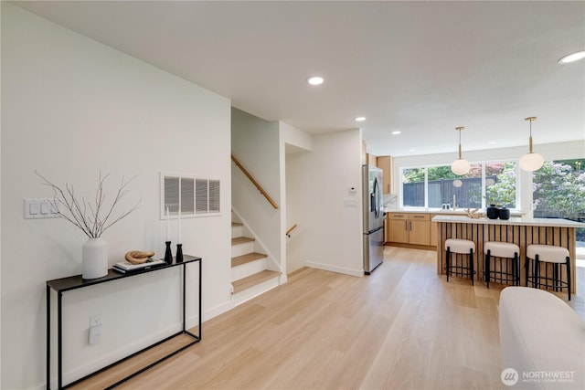 kitchen featuring stainless steel fridge with ice dispenser, recessed lighting, light wood-type flooring, light countertops, and plenty of natural light