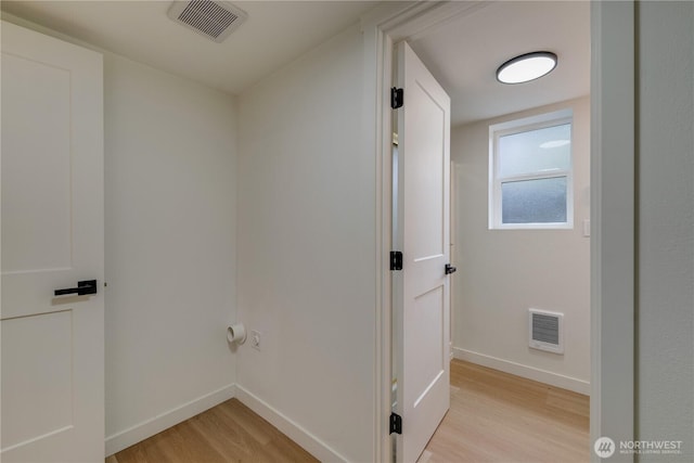 corridor with light wood-type flooring and baseboards