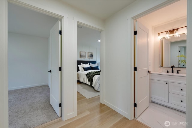 hall with a sink, baseboards, and light wood-type flooring