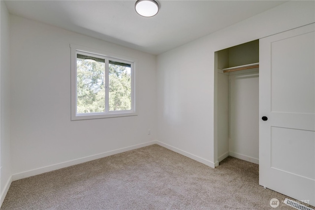 unfurnished bedroom with light carpet, baseboards, and a closet
