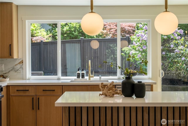 kitchen with backsplash, a sink, light countertops, and plenty of natural light