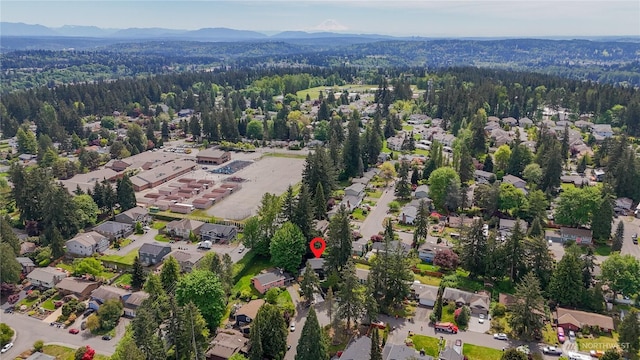 aerial overview of property's location featuring a mountain backdrop, a forest, and nearby suburban area
