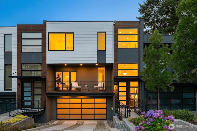 view of front of home with an attached garage, driveway, and a balcony
