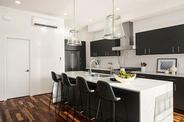 kitchen featuring a wall mounted air conditioner, high end fridge, dark cabinets, a sink, and extractor fan