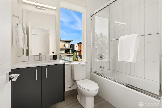 bathroom featuring toilet, vanity, and combined bath / shower with glass door